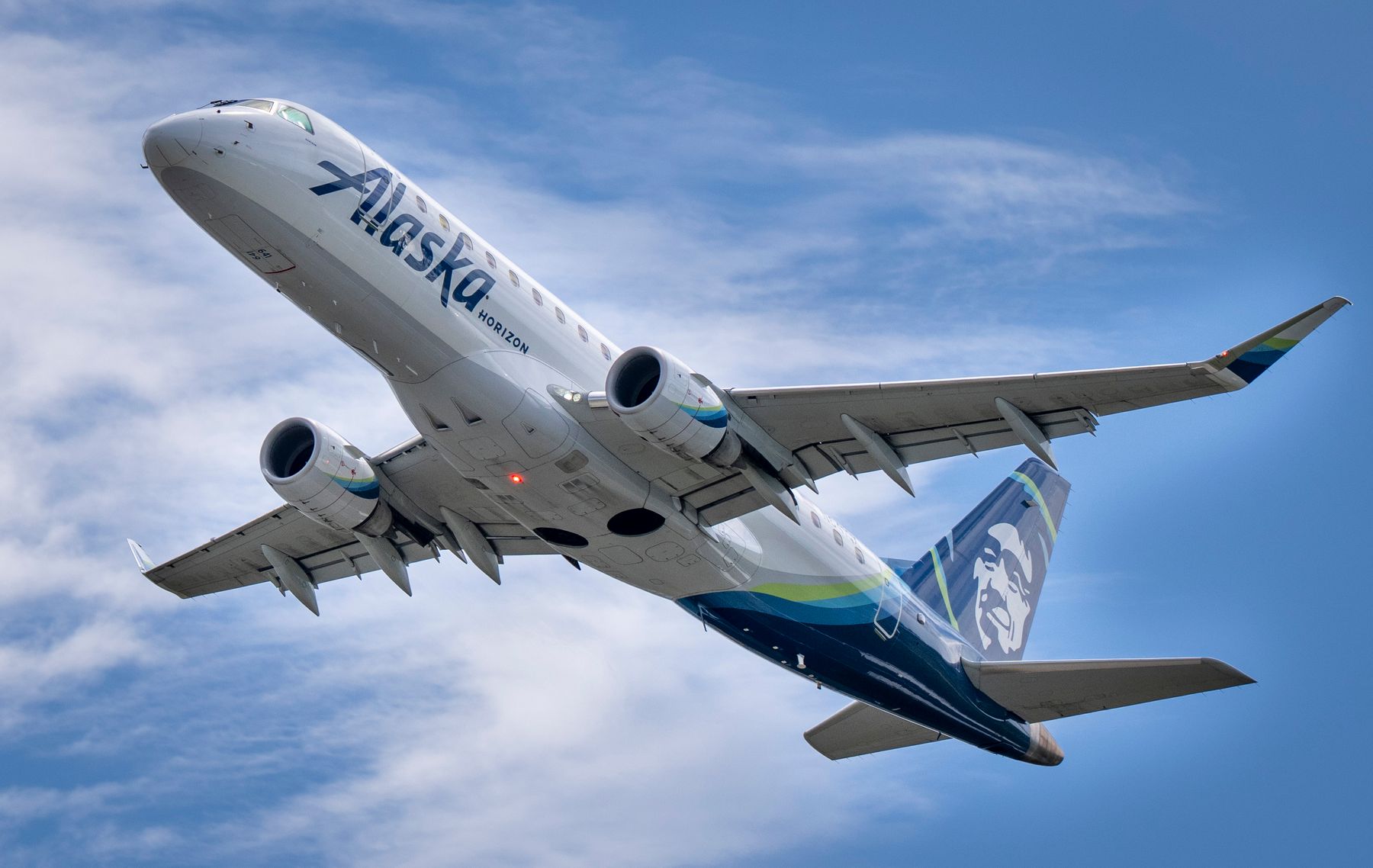 Alaska Airlines Horizon jet climbing against a blue sky