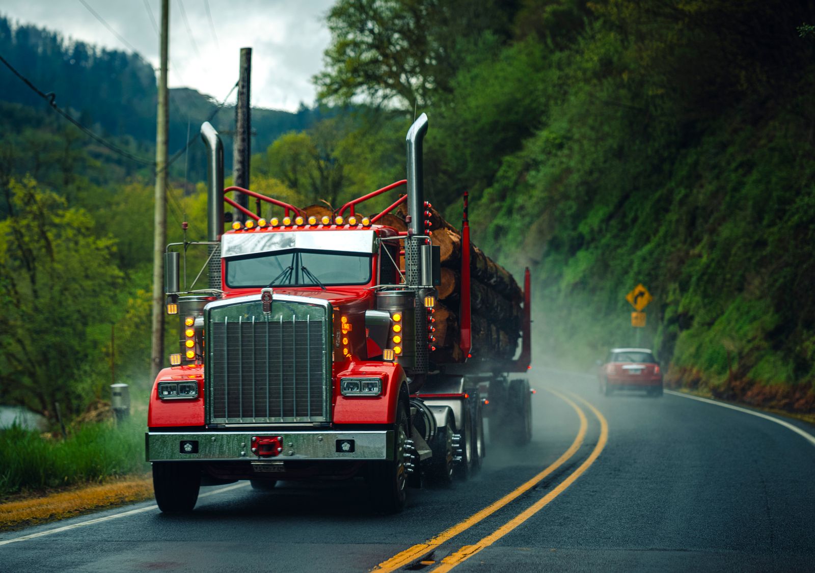 Red Kenworth logging truck on a wet Oregon highway